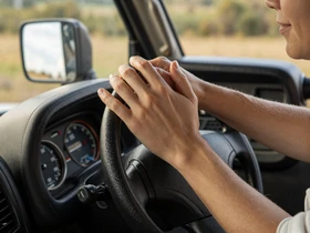 Couple holding hands on a truck steering wheel - trucker dating road trip moment